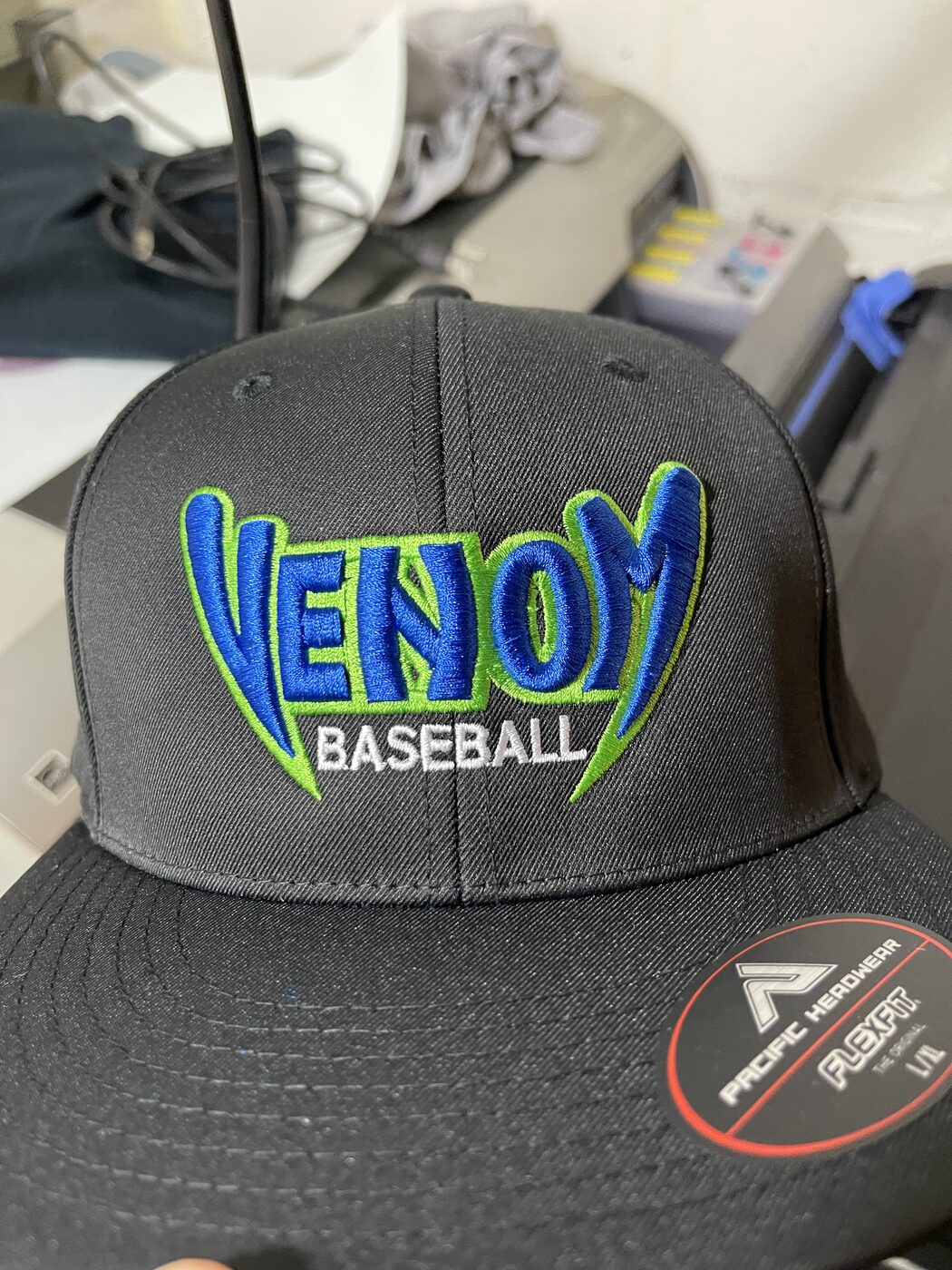 Black flat-brim cap with blue and green Venom Baseball 3D puff embroidery.
