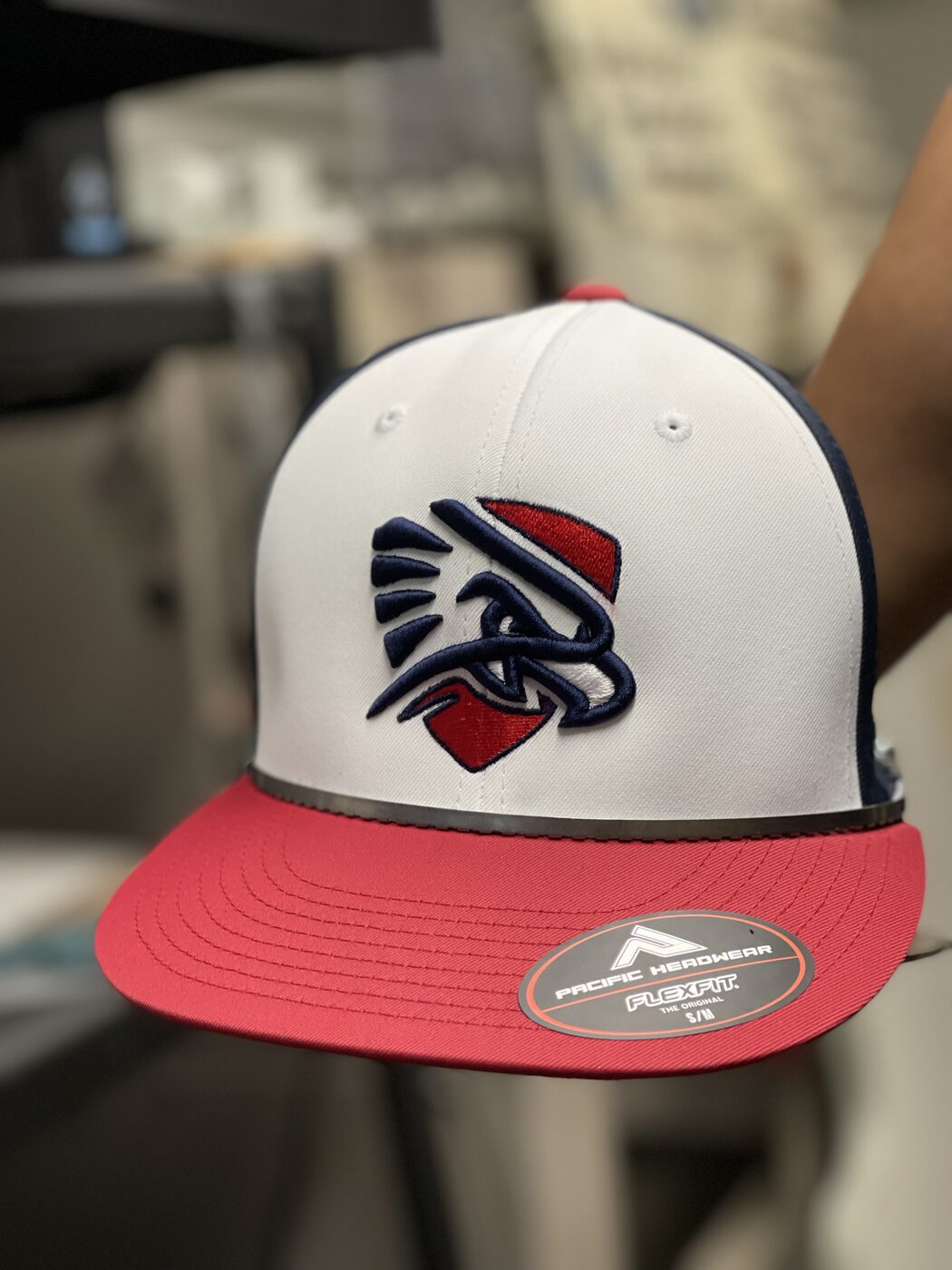 White, navy, and red flat-brim cap with embroidered eagle logo.